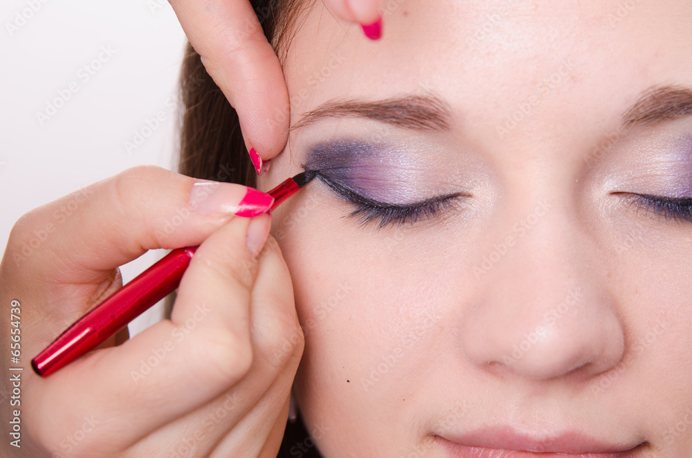 Bright makeup. Makeup artist begins to draw arrows