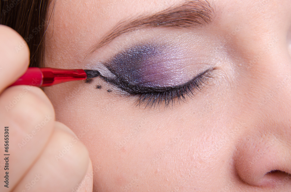 Makeup artist draws arrows on the eyelids model