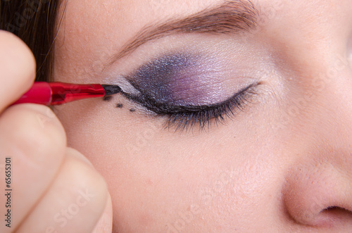 Makeup artist draws arrows on the eyelids model © madhourse