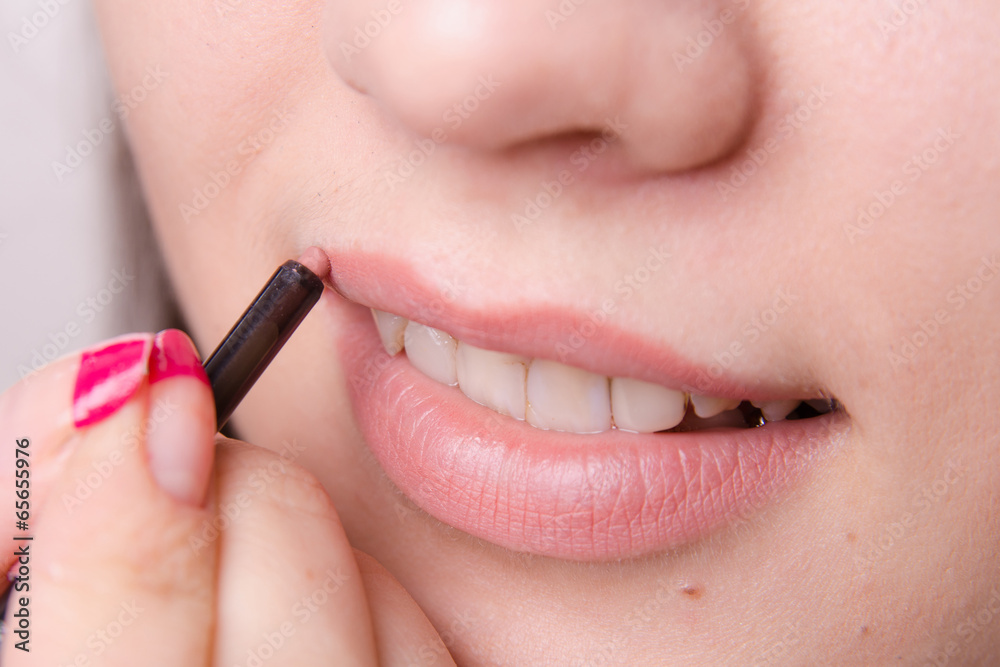 Makeup artist paints a lip pencil woman