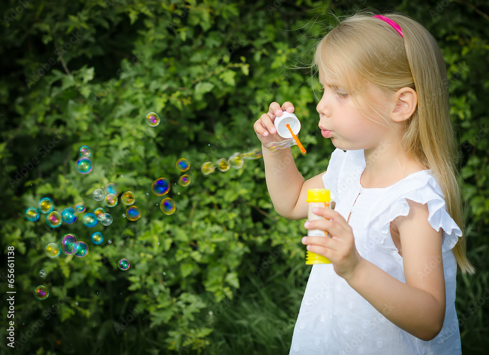 Little girl blowing soap bubbles in the park. Little girl blowing soap bubbles in the park.