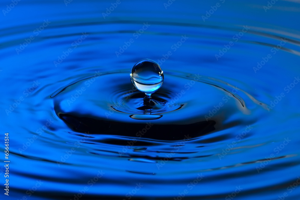 Water drop close up with concentric ripples colourful blue surfa