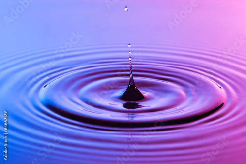 Water drop close up with concentric ripples colourful blue and p