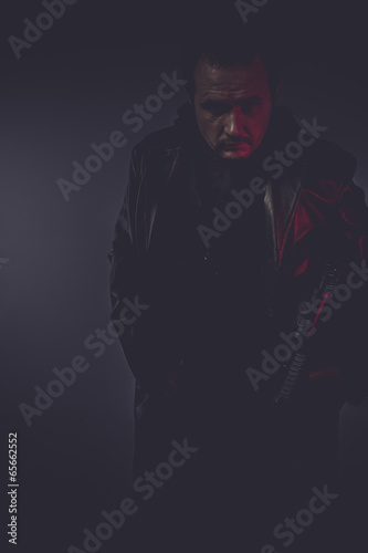 shadow portrait of stylish man with long leather jacket, gun arm