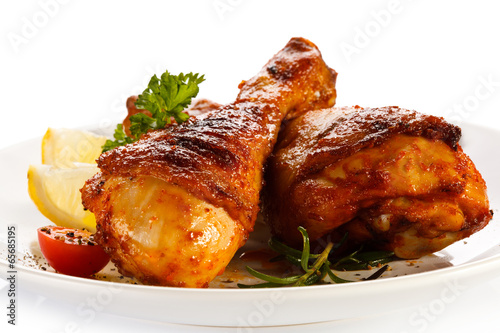 Grilled chicken legs and vegetables on white background