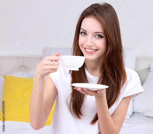 Young beautiful woman on bed with cup of coffee