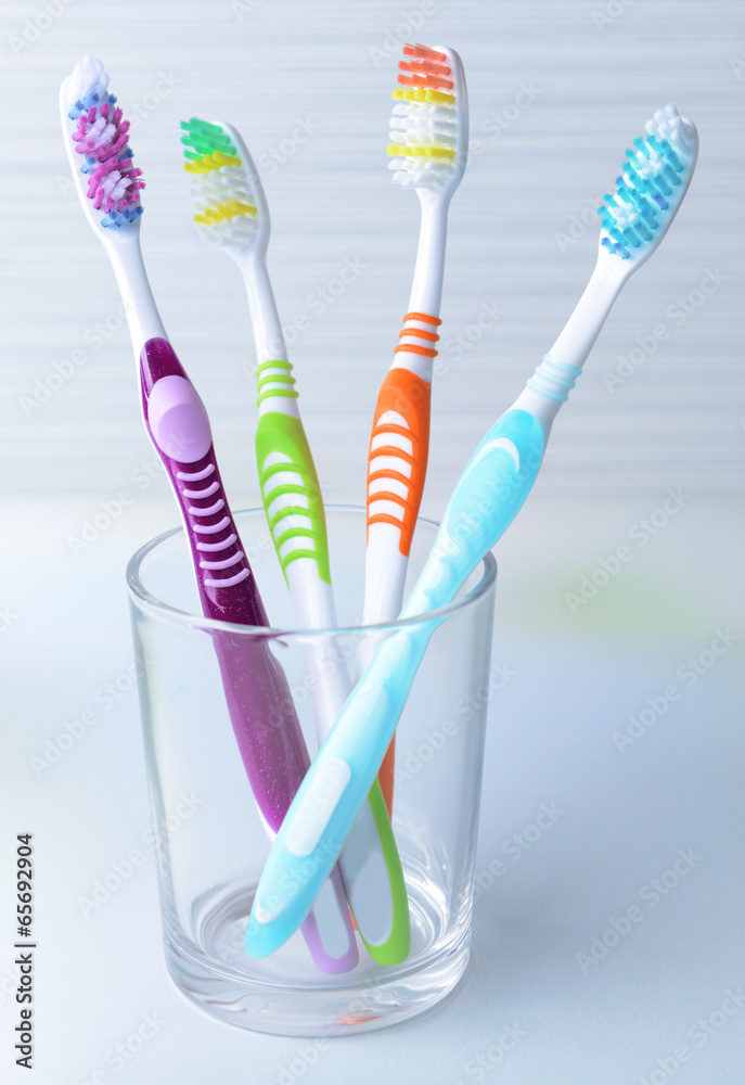 Toothbrushes in glass on table on light background Toothbrushes in glass on table on light background