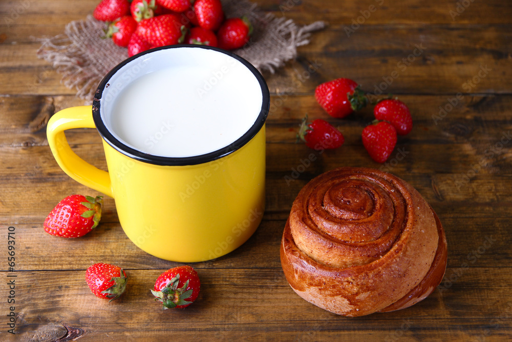 Ripe sweet strawberries, fresh bun and mug with milk