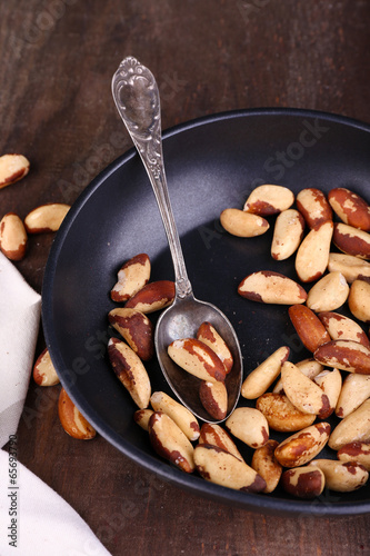 Tasty brasil nuts in pan on wooden background