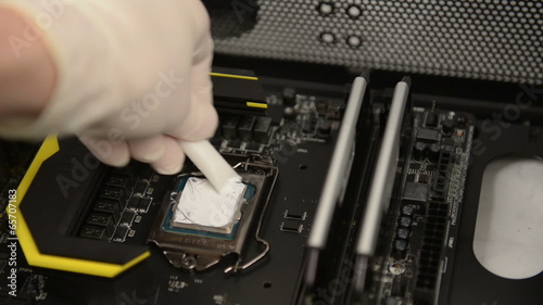 Technitian applies thermal paste on CPU photo