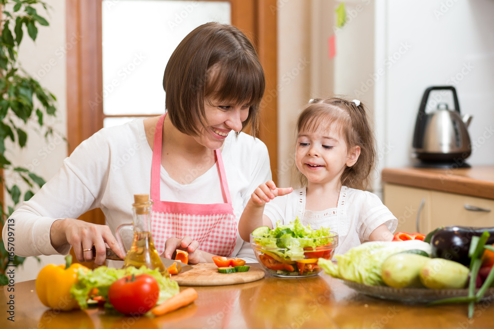Young woman and her child daughter making vegetable salad Young woman and her child daughter making vegetable salad