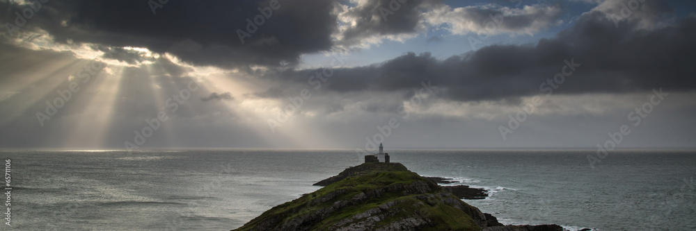 Landscape panorama of Mumbles lighthouse in Wales with sunbeams