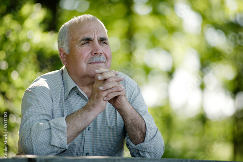 фотографія Elderly man sitting in the garden thinking