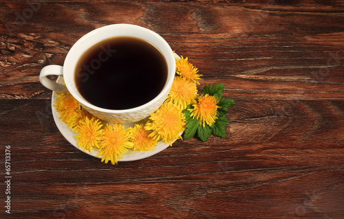 Coffee mug surrounded by dandelions on a wooden background.