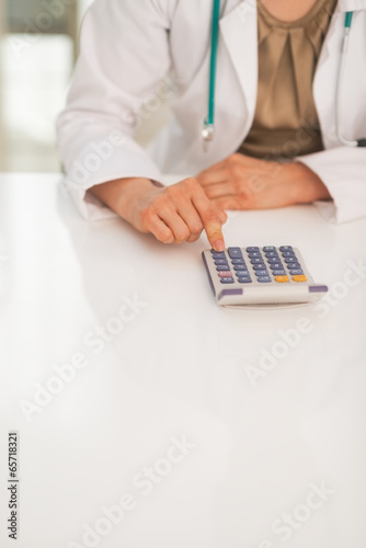 Closeup on medical doctor woman using calculator