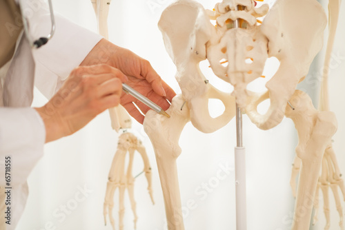 Closeup on doctor woman pointing on femur of human skeleton photo