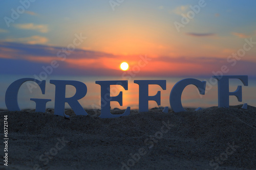 Seascape with sunset and white word Greece on sand