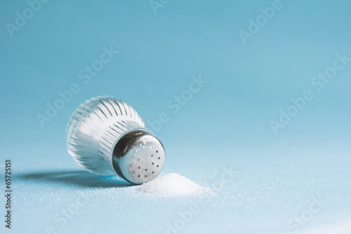 Photos Spilled salt and saltshaker on blue background