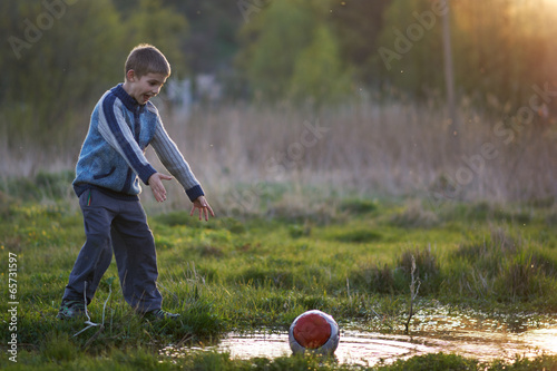 Fotografija boy dropped the ball in a puddle and shouts
