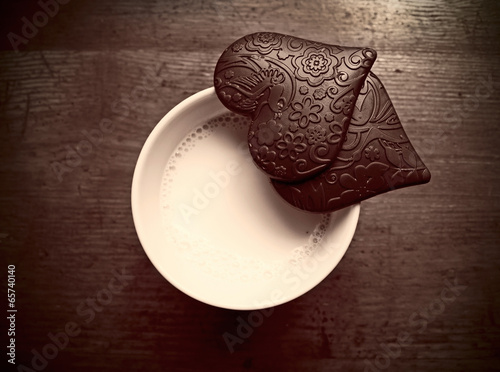 Cup of milk and two heart-shaped pieces of chocolate