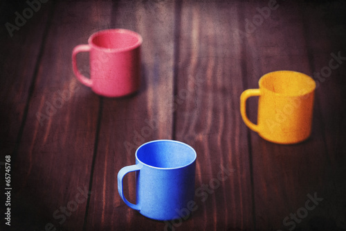 Three color cups on woodent table.
