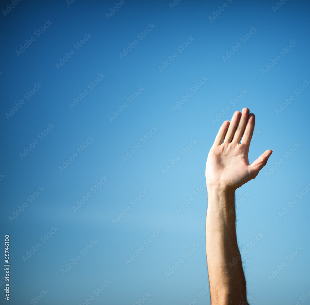 Raising hand with hand palm against blue sky Raising hand with hand palm against blue sky