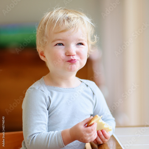 Cute toddler girl eating sandwich in the morning