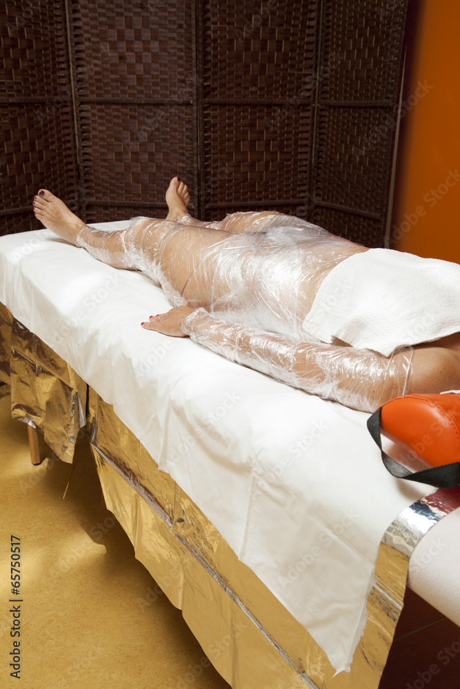 Obraz premium Female body being wrapped around with foil to reduce fat