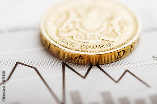 Fotografija One pound coin on fluctuating graph