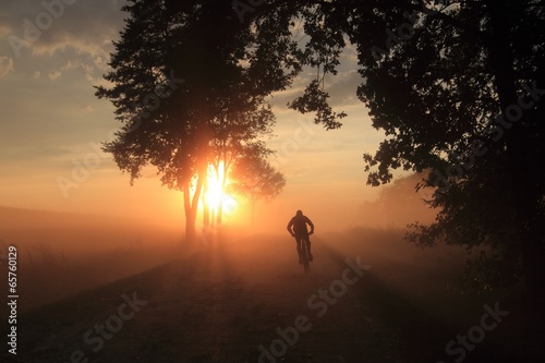 man on a bicycle in a misty landscape