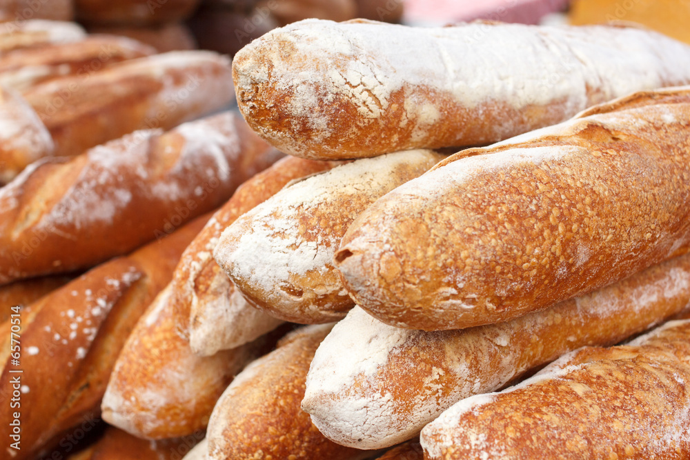 Many loaves of bread stacked in a market environment.