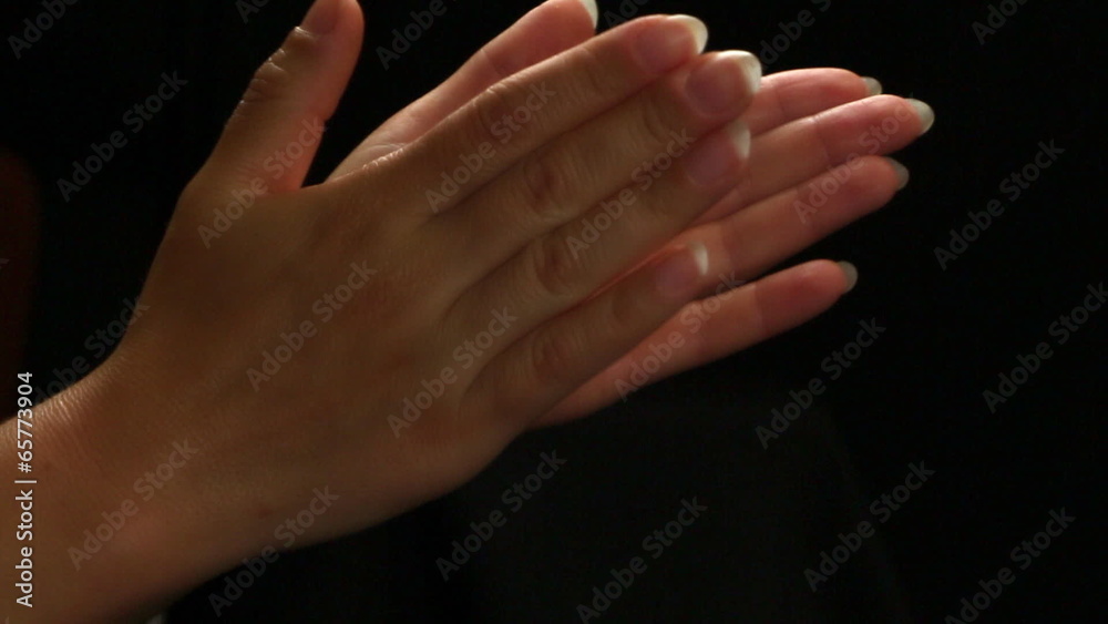 Female hands applaud on a black background, close up Female hands applaud on a black background, close up