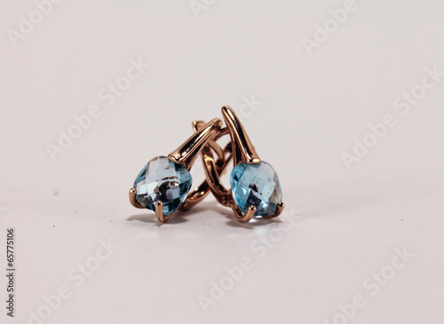 Jewelry. Gold earrings with blue Topaz. Isolated object on white photo