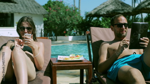 Couple using modern technology in the swimming pool photo