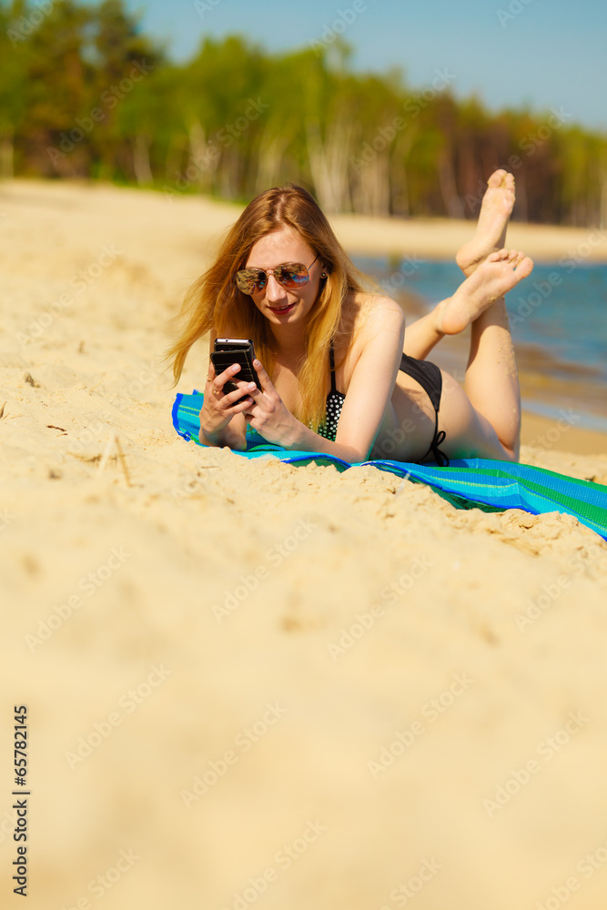 Summer vacation Girl with phone tanning on beach Summer vacation Girl with phone tanning on beach