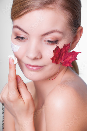 Skin care. Face of young woman girl with red maple leaf.