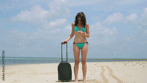 Woman with suitcase get lost on the beach photo