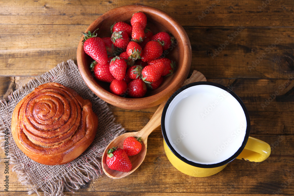 Ripe sweet strawberries in wooden bowl and jug with milk