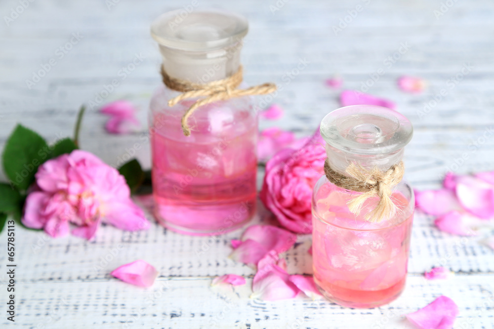 Rose oil in bottles on color wooden background Rose oil in bottles on color wooden background