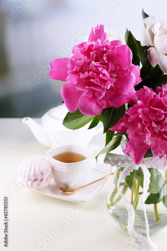 Composition of beautiful peonies in vase  tea in cup and