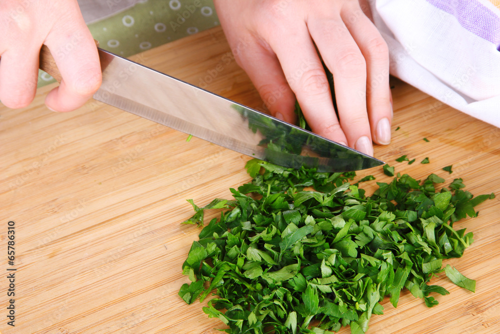 Female hand cutting greens on cutting board Female hand cutting greens on cutting board