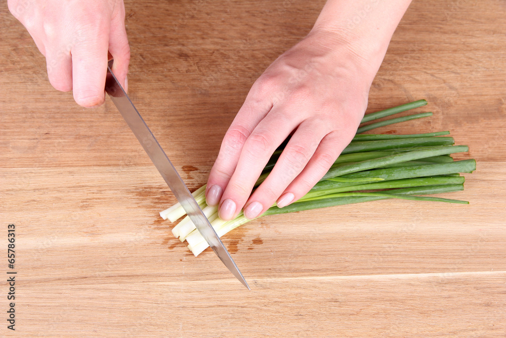 Female hand cutting chives on cutting board Female hand cutting chives on cutting board