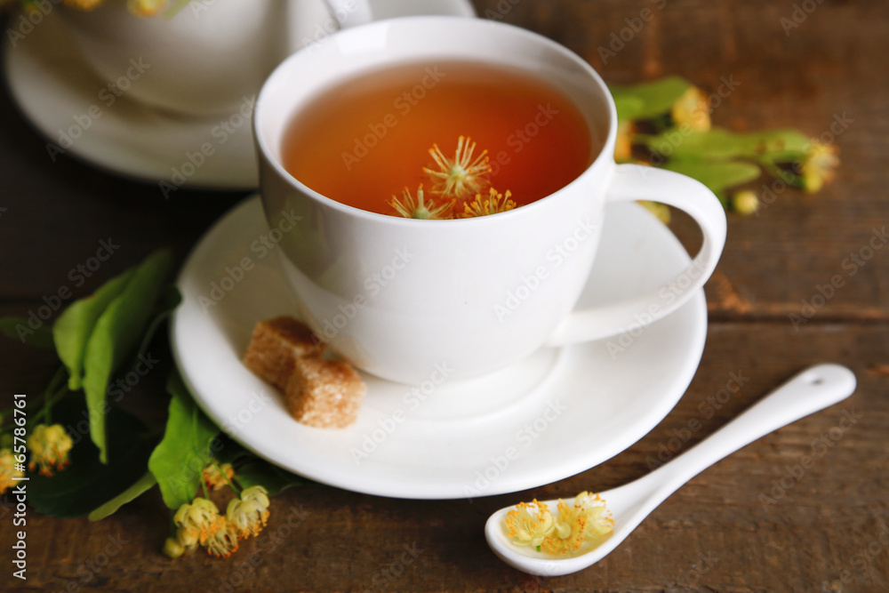 Tasty herbal tea with linden flowers on wooden table Tasty herbal tea with linden flowers on wooden table