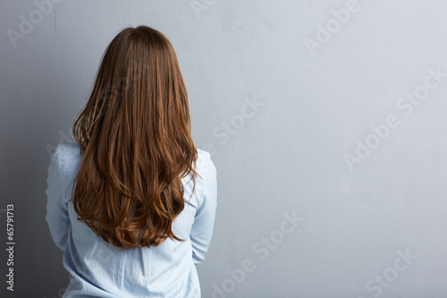 Business woman standing back against gray wall. photo