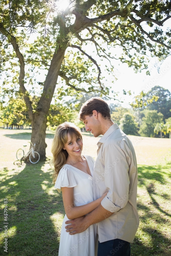 Fototapeta premium Smiling couple standing and embracing in park