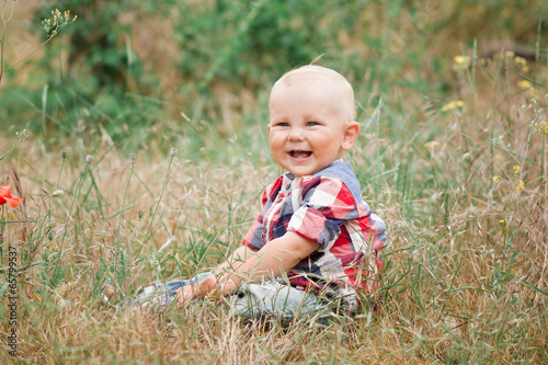 Fashion baby boy wearing checkered shirt walking in grass