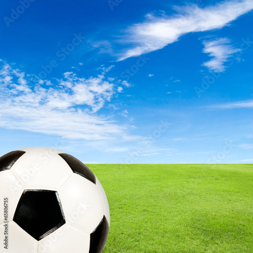 soccer ball with green grass field against blue sky