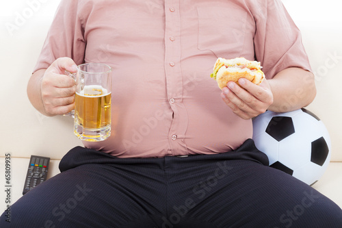 fat business man eating food and beer and sitting on sofa