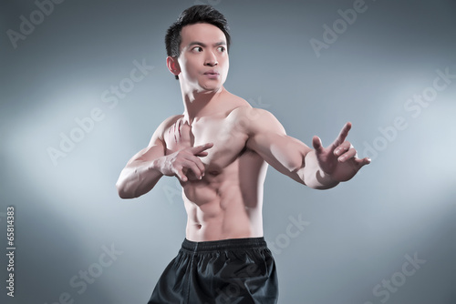 Fotografie, Obraz Muscled asian kung fu man in action pose. Blood stripes on his c