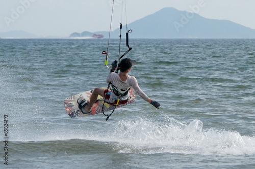 Male kite surfer jumping with ferry behind